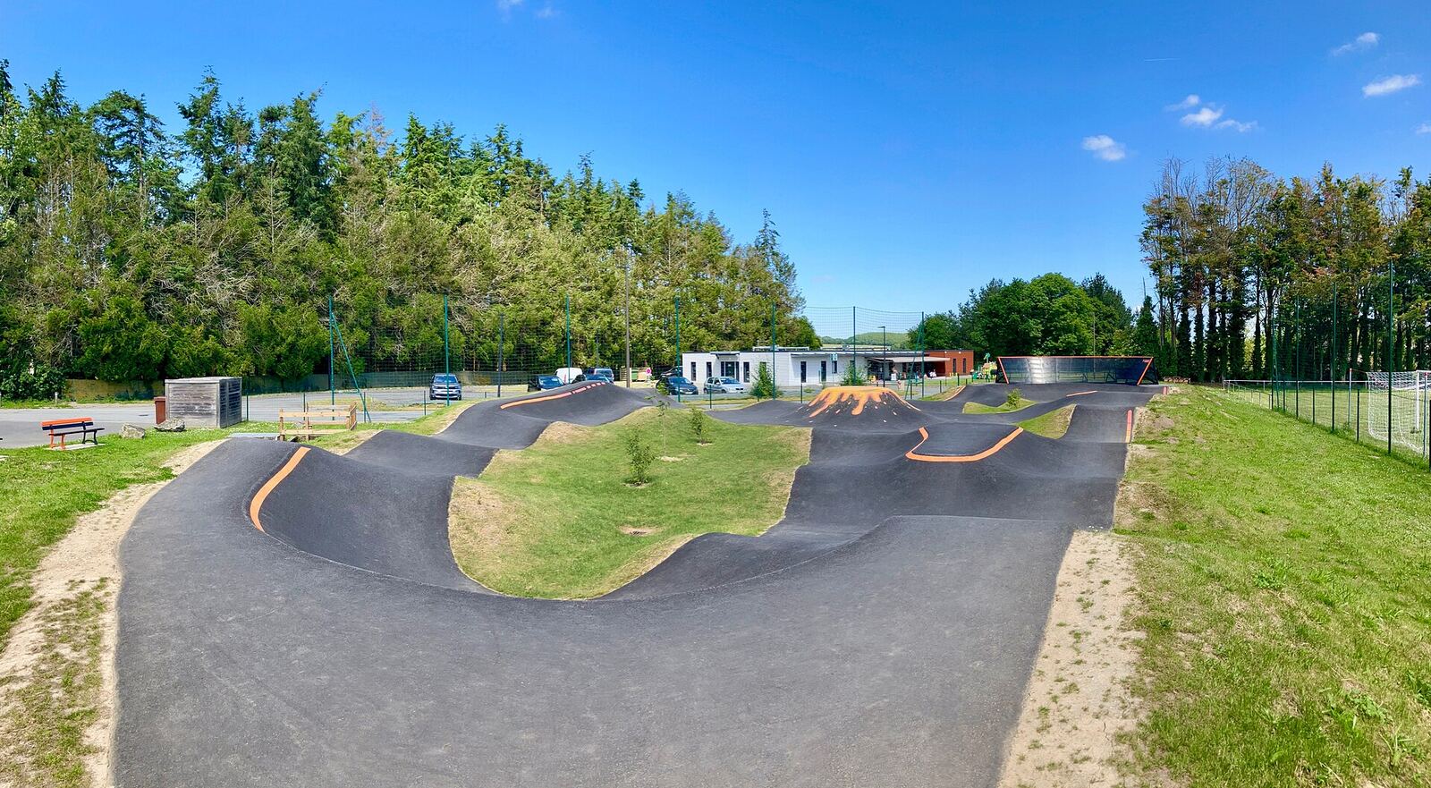 Un pumptrack en asphalte aux virages relevés, au bord d'un bois à Corseul en Bretagne