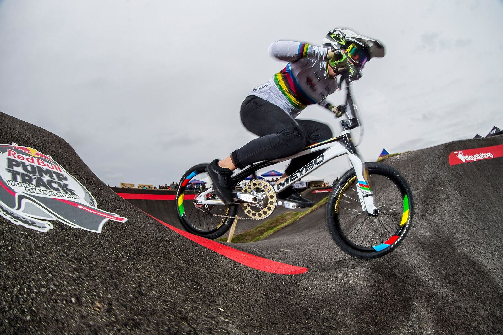 Un pilote de BMX penché dans un virage relevé d'un pumptrack en asphalte